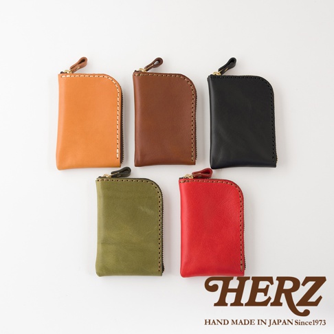 五款不同顏色的日本HERZ職人手作皮革分隔收納迷你錢包整齊排列，採用Stare皮革製成，表面呈現細膩質感與車縫線細節，設計簡約精緻並附有拉鍊，右下角標示品牌名稱與產地資訊。