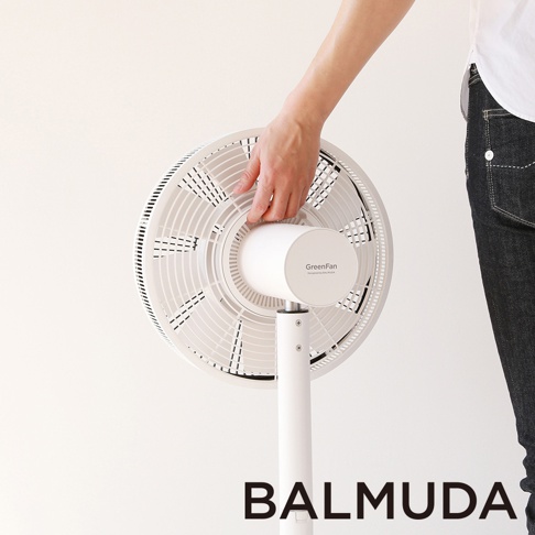 白色立扇，圓形扇葉網罩，中央有「GreenFan」標誌，由人手從側面觸碰扇葉網罩。