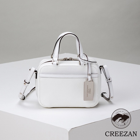 JETTER 迷你箱型包，白色皮革材質，設有雙提把、可拆卸斜背帶，正面有拉鍊夾層，並掛有品牌金屬吊牌。
