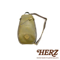 橄欖綠皮革斜背包，配有金色拉鍊和可調節肩帶。包身有一個傾斜拉鍊口袋和一個菱形皮革標誌，上面印有「HERZ」字樣。