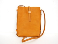 職人手作皮革散步直式單肩包 (CP-3)，採用淺棕色牛皮製成，包體為直立式長方形設計，正面中央有一條皮革束帶開合，側邊有可調節的細長皮革背帶。