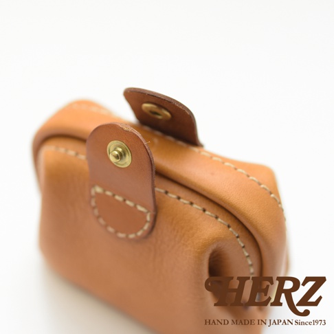 職人手作皮革口金化妝包 KF-143 S，展現自然棕色皮革紋理，搭配縫線與金色金屬釦，小巧精緻。