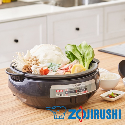 鐵灰色圓形電鍋，內盛滿豐富食材，包含大白菜、青江菜、金針菇、香菇、肉片、蟹肉棒、餃子等，旁邊另有白飯和沾醬。