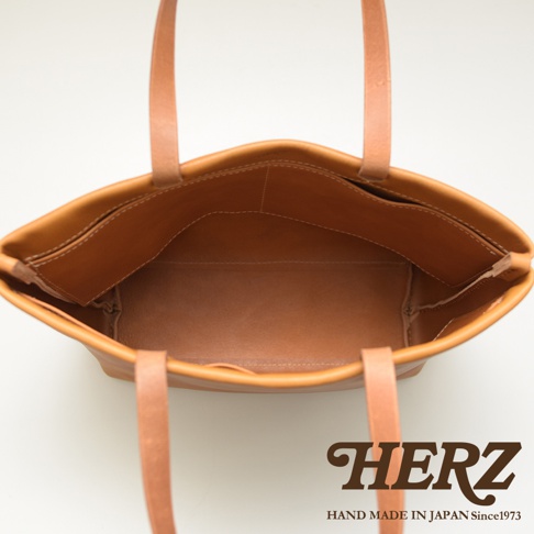 職人手作的淺棕色皮革托特包，內部有四個開放式口袋，簡潔設計，適合日常使用。