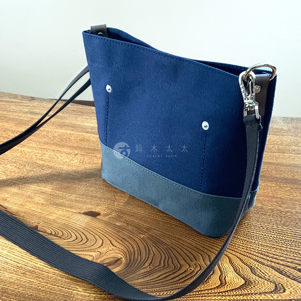 犬印純綿帆布雙色迷你側背包，深藍色主體搭配灰色底部，簡約設計，配有可調節黑色背帶及銀色金屬扣環。