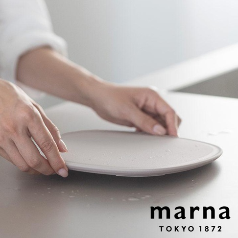 marna TOKYO 1872 品牌淺色圓盤，由雙手輕輕扶著