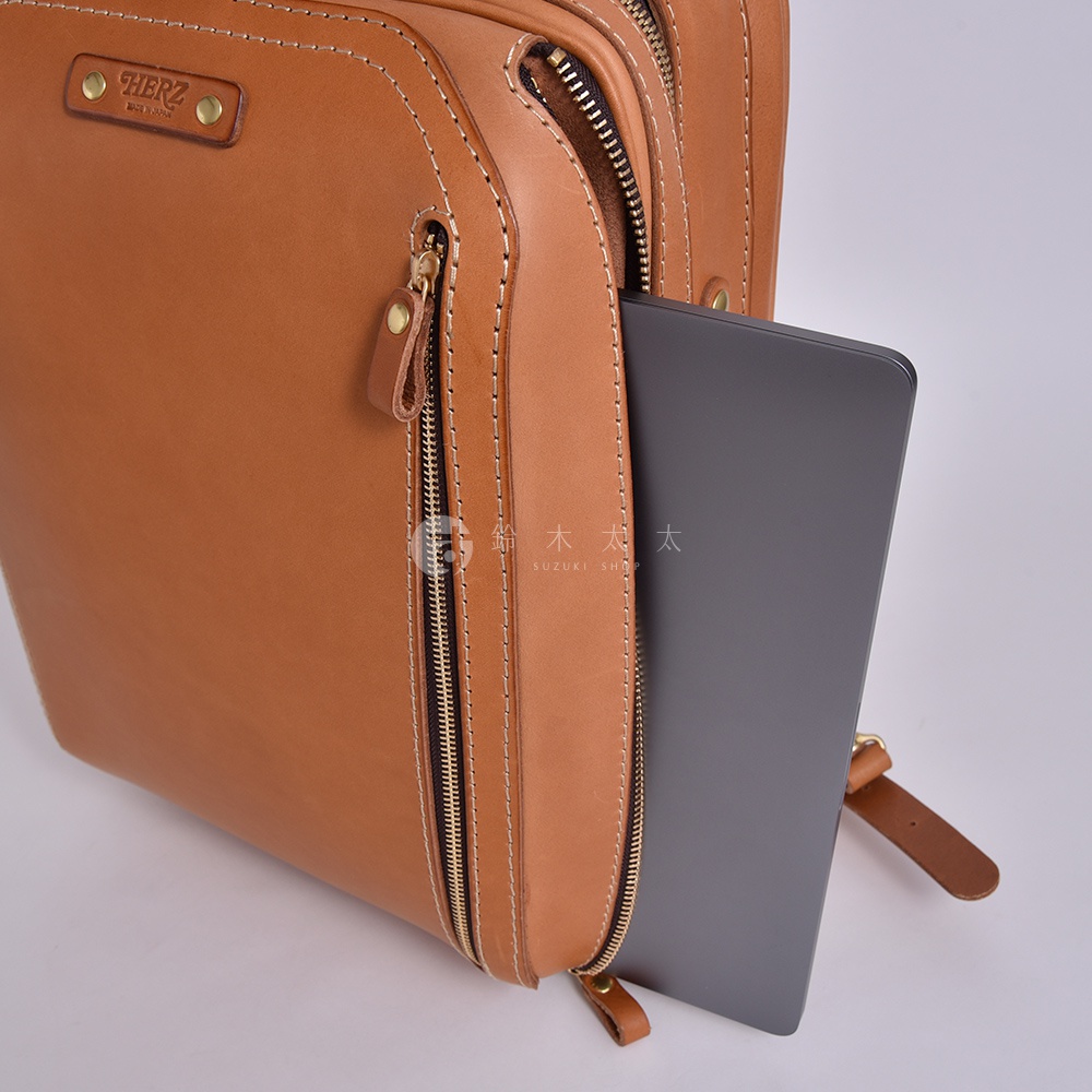 駝色皮革兩用商務後背包，有拉鍊側袋，內可放入平板電腦。包身有精緻縫線及品牌標誌，材質為真皮。