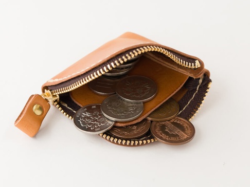 淺棕色皮革零錢包，拉鍊開啟，內部裝有日圓硬幣，皮革製成，搭配金色拉鍊和黃銅按扣。
