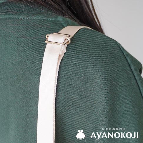 A white strap with a silver buckle is attached to the shoulder of a person wearing a dark green sweatshirt. The AYANOKOJI logo is visible in the lower right corner.
