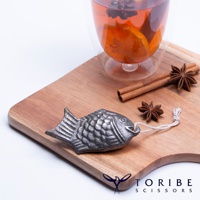 銀灰色、魚形狀的補鐵小鯛魚，帶有白色細繩，放置在木質砧板上，旁邊有肉桂棒和八角。