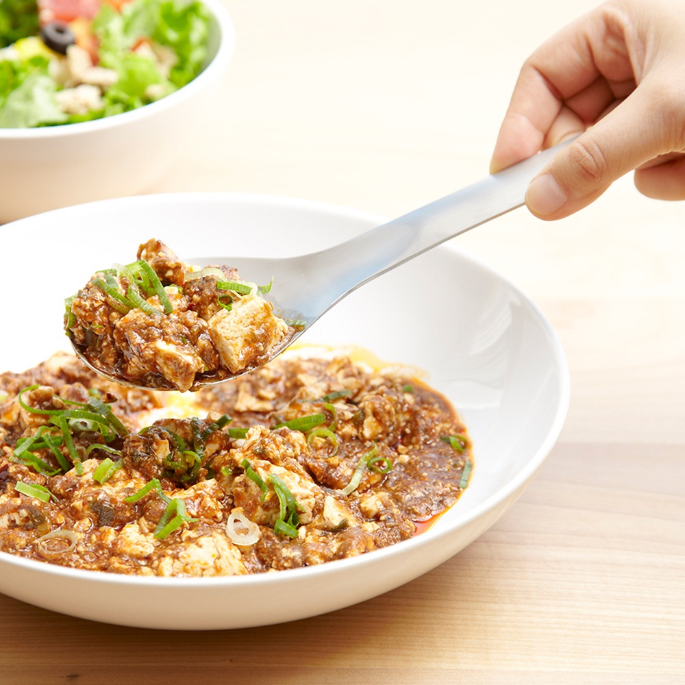 日製服務餐匙，不鏽鋼材質，匙面盛有麻婆豆腐，上方撒有蔥花，一隻手正握持餐匙。
