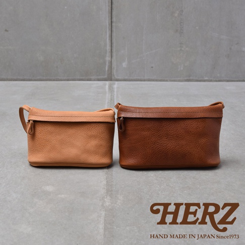 兩個皮革手拿包，一個為淺棕色，一個為深棕色，皆為職人手作。