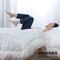 一名女子平躺在被子中，雙腿彎曲抬起，露出穿著牛仔褲的腳踝。