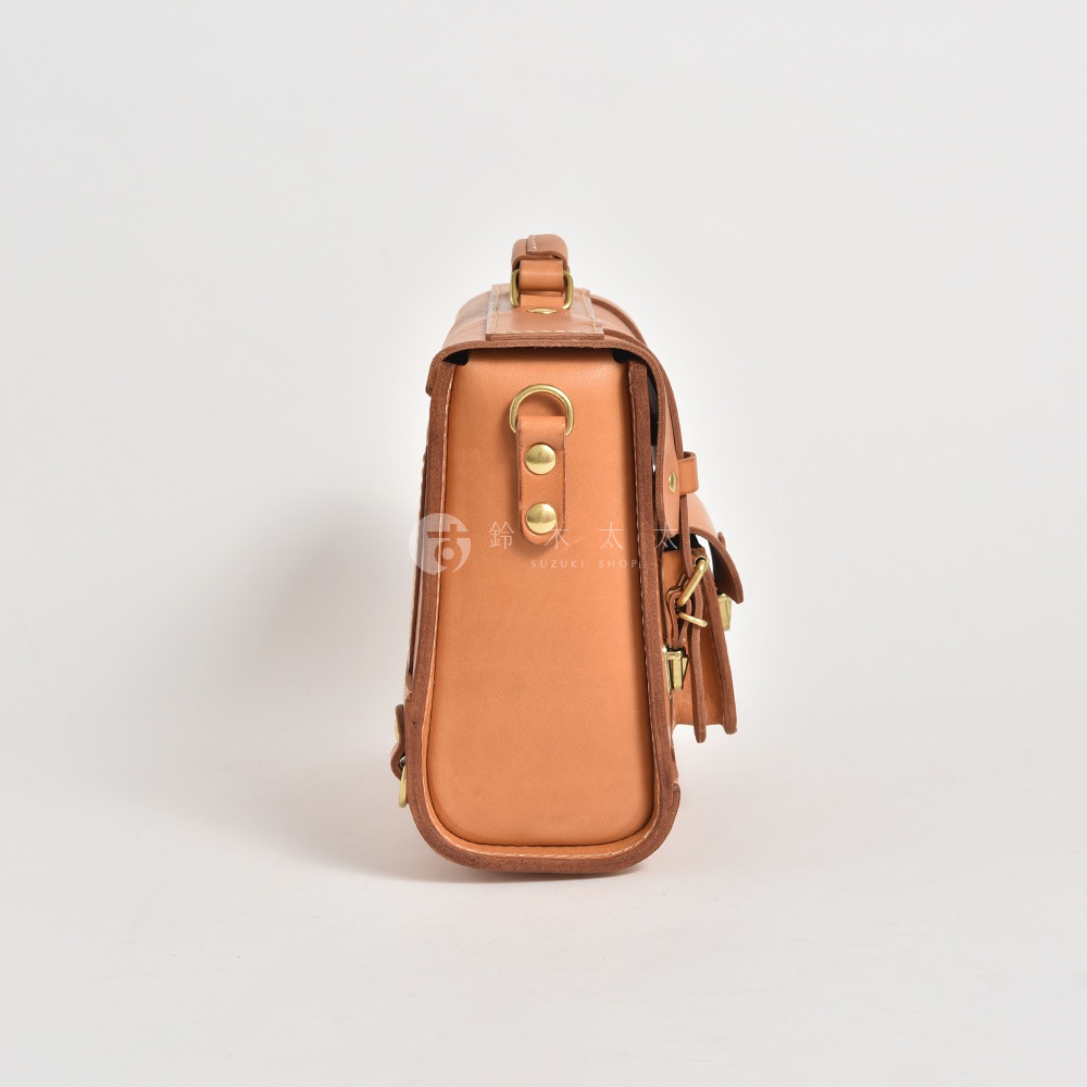 皮革學院風三用迷你後背包，淺棕色，側面視角，展示其皮革材質、金屬釦環及提把設計。