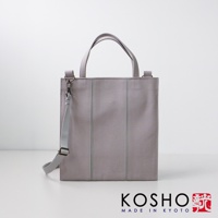 淺灰色棉帆布托特包，兩側有垂直縫線，配有提把和可拆卸肩帶，包包正面左側有銀色金屬扣環。