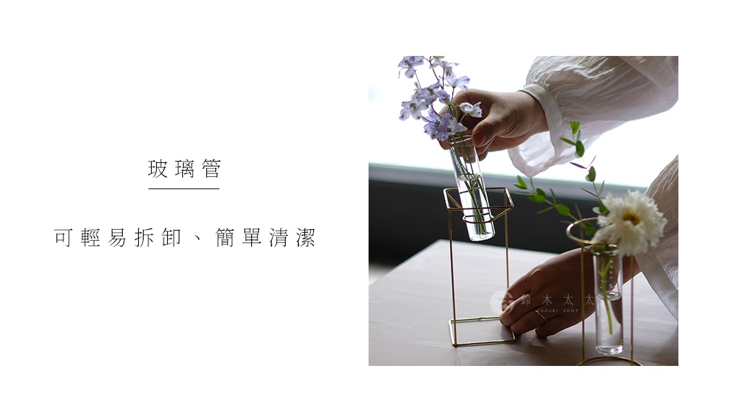 黃銅圓柱玻璃花器，內插紫色小花束，搭配金屬支架，現代簡約設計。