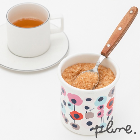 琺瑯材質的儲物罐，罐身印有多彩花朵圖案，內裝紅糖並附有木柄金屬湯匙。