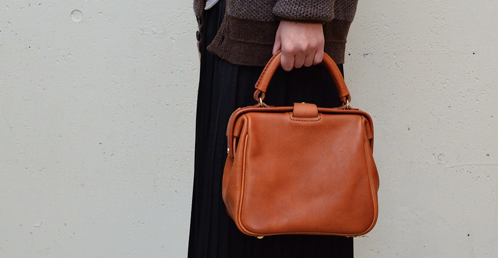 職人手作方形口金托特包，採用棕色皮革，設有頂部提把和金色金屬扣。