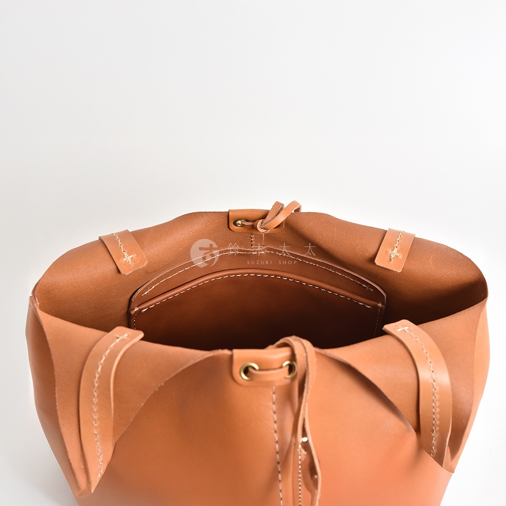 職人手作皮革球形肩掛托特包，特寫內部，展示焦糖棕色皮革材質、縫線細節及內袋。