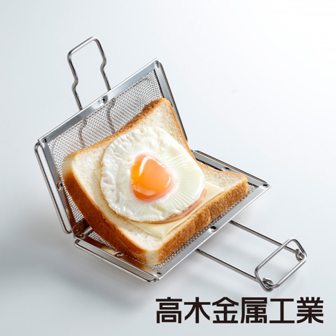銀色不鏽鋼網狀烤箱用吐司夾，裝有兩片吐司、起司和一顆煎蛋，吐司夾有提把和可伸長的握把。