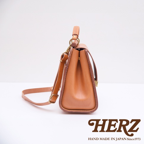 日本HERZ職人手作皮革屋瓦風兩用單肩包，棕色皮革，側邊視角，展現精湛工藝與耐用材質，搭配品牌標誌。