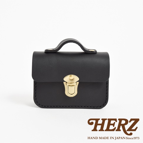 黑色皮革迷你收納包，配有金色金屬鎖扣和提把，簡潔的設計展現職人手作質感。