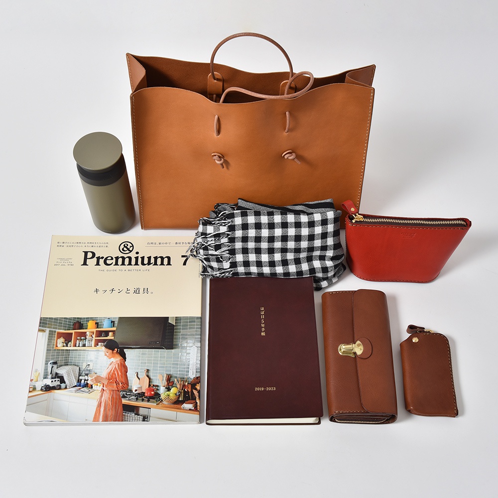 咖啡色皮革托特包、綠色保溫杯、黑白格紋圍巾、紅色化妝包、棕色長夾、鑰匙包及一本雜誌。