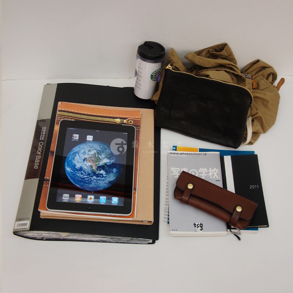 職人手作皮革軟式杜勒斯包，黑色皮革，附黃銅拉鍊，搭配卡其色衣物、平板電腦、咖啡杯和筆記本。