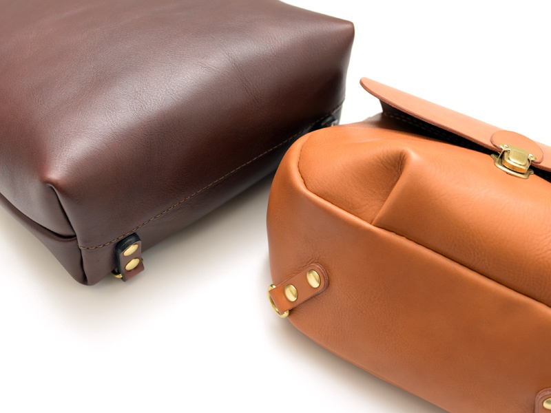 職人手作皮革屋瓦風迷你後背包 (R-6)，一個深棕色皮革後背包，底部有兩個黃銅色金屬扣件，以及一個淺棕色皮革後背包，有翻蓋和黃銅色金屬鎖扣。