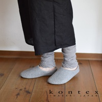 灰色針織襪套，材質輕薄，可堆疊於腳踝處，搭配一雙灰色針織室內拖鞋。