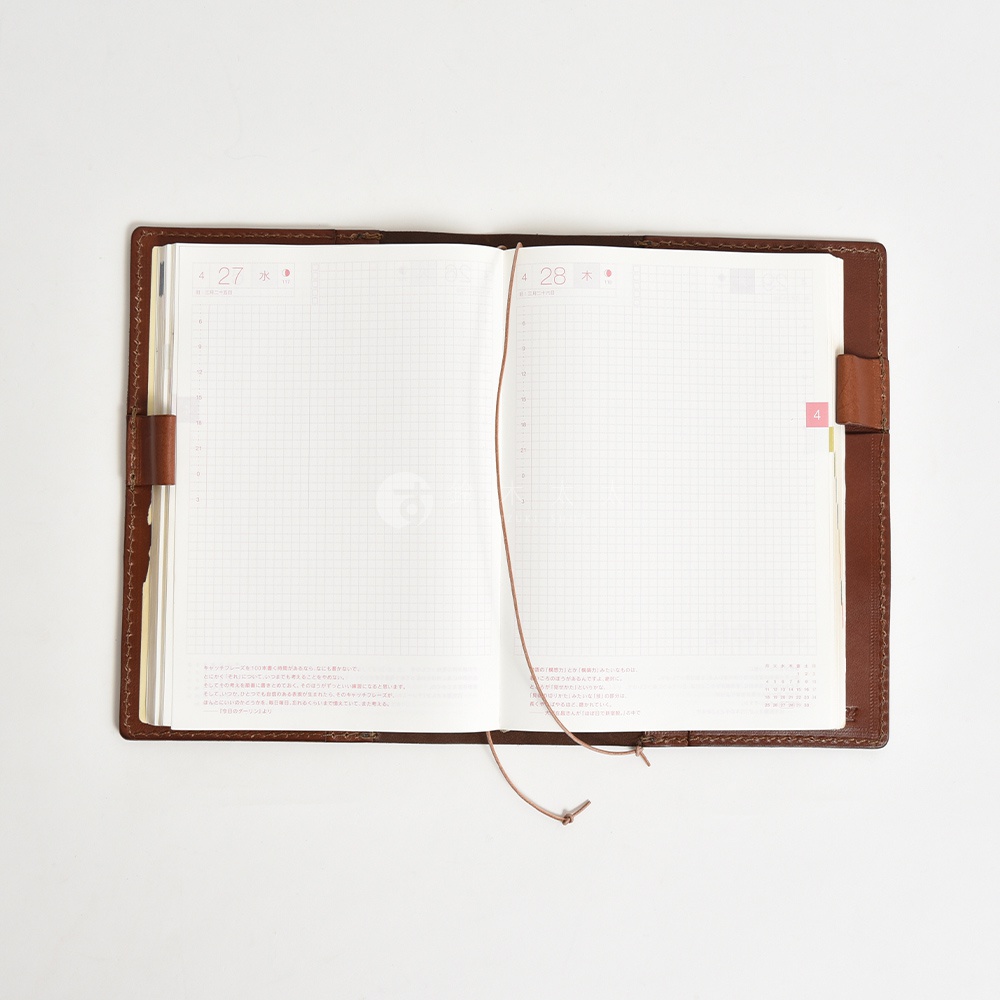 一本棕色皮革封面打開的手帳，內頁為白色網格，顯示日期為4月27日和4月28日，並有少量日文說明文字。