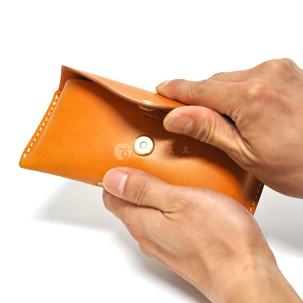 皮革眼鏡收納盒，橘棕色，附有金色按扣，由雙手展示