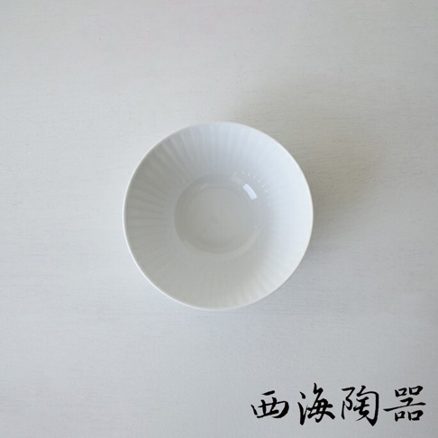 白色陶瓷碗，外緣有放射狀凹槽紋理，碗底平滑，表面光滑，產品名稱「波佐見燒 花 FUWARI」標示於角落。