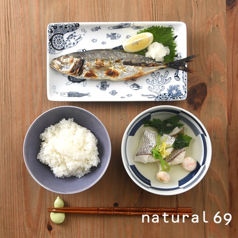 長方餐盤上盛有烤魚、檸檬片、蘿蔔泥和紫蘇葉，盤身印有藍色魚紋。旁邊是盛有白飯的灰色圓碗和盛有魚肉湯的藍白條紋圓碗。