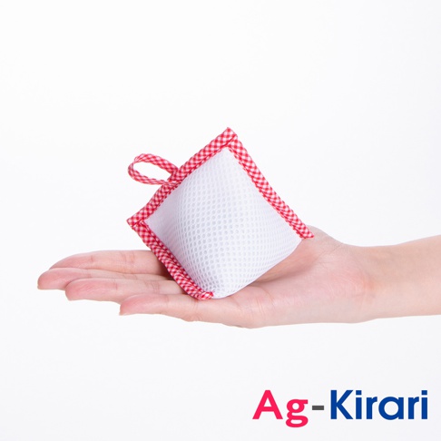 手掌上托著一個白色網狀材質、邊緣為紅色格紋的方形洗衣槽去污包，上方有紅色格紋提帶。