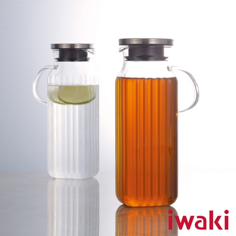 兩個方形耐熱玻璃水壺，一個裝有檸檬片和水，另一個裝有琥珀色飲料。水壺均配有不鏽鋼蓋和玻璃把手，瓶身有垂直壓紋。