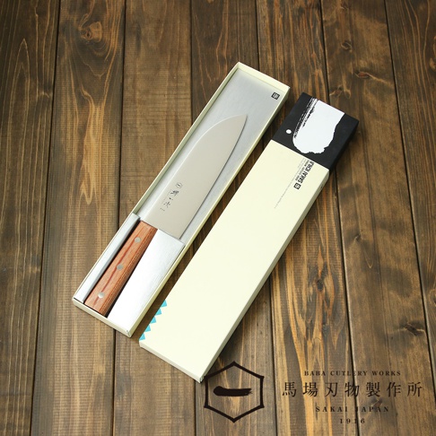 [堺一次] 不鏽鋼三德刀，刀刃為銀色不鏽鋼材質，木柄為茶色，刀身有日文刻字，產品置於銀色內襯的紙盒中，旁有一淺米色紙盒。