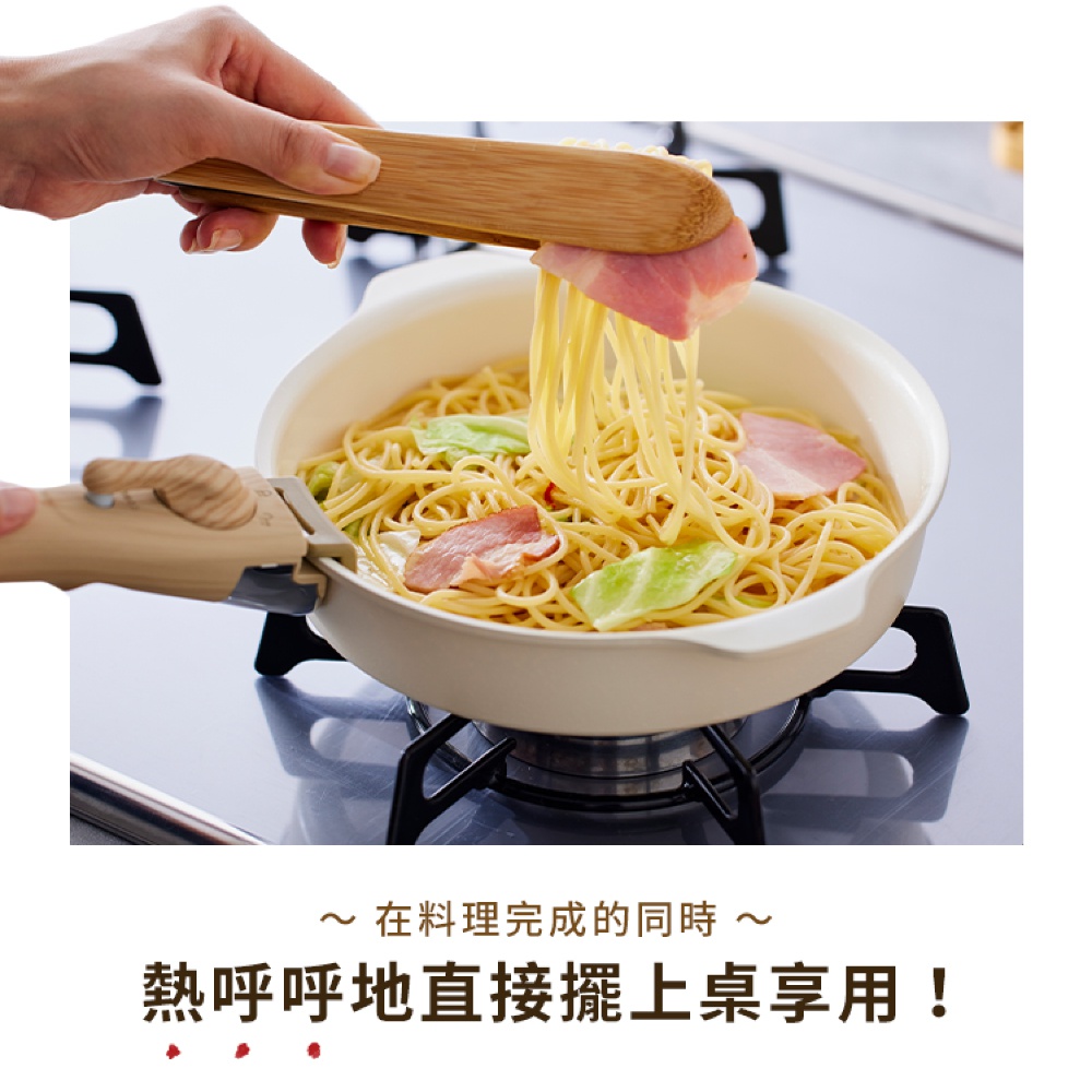 淺色陶瓷不沾平底鍋盛有義大利麵、培根和蔬菜，由木製夾子夾起麵條，鍋具下方有可拆卸的淺棕色把手。