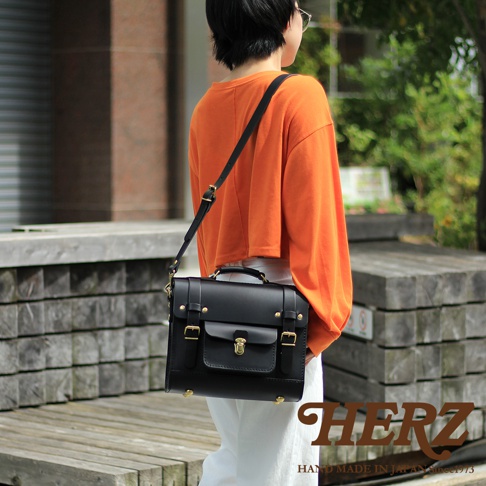 黑色皮革學院風三用迷你後背包，配有翻蓋、金屬鎖扣、皮帶扣和頂部提把，可肩背或斜背。