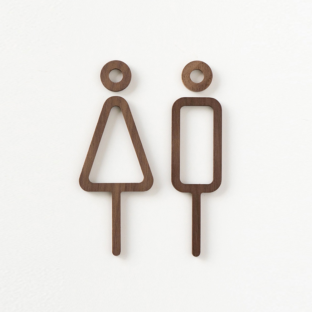 一對木製的男女廁所標示牌，以簡約線條勾勒出女性（三角形）與男性（長方形）的圖案，材質為深棕色木頭，整體造型呈現現代風格。