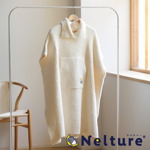 柔軟的白色起司斗篷掛在衣架上，斗篷上有一個口袋和領子，下方有 Nelture 的品牌標誌。