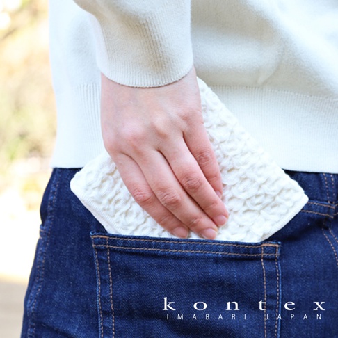 白色棉麻混紡方巾，表面有鬆餅紋路，被塞入深藍色牛仔褲的後口袋。