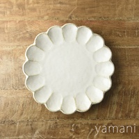 一個 24 公分、白色、帶有六瓣花型邊緣的陶瓷主食盤，表面有細微的紋理，盤底有「yamani」品牌標誌，置於木紋背景上。
