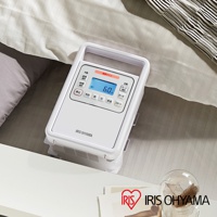 白色IRIS OHYAMA強力被褥乾燥機，頂部有提把，正面有顯示螢幕和多個日文按鈕，螢幕顯示「60」分鐘，產品放置在床上。