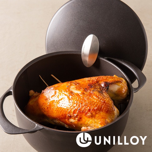 黑色琺瑯鑄鐵鍋內放有一隻烤雞，鍋蓋半開，上面有一個銀色金屬把手，上面刻有「UNILLOY」字樣。