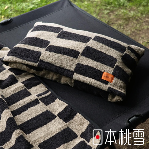 日本桃雪戶外格紋浴巾，觸感柔軟，帶有品牌標籤，置於露營椅上