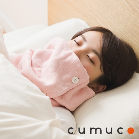 一位女子在床上睡覺，粉色頸套蓋住她的嘴巴，一旁有CUMUCO的品牌標誌。