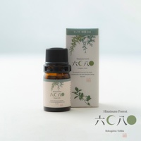 琥珀色玻璃瓶裝有檜木萃取純精油，黑色瓶蓋，瓶身上有淺米色標籤，印有綠色樹枝圖案及日文與英文品牌名稱「Hisatsune Forest」與「Rokugatsu Yohka」，旁邊為同款設計的綠色紙盒。