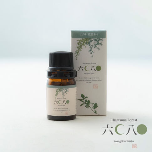 琥珀色玻璃瓶裝有檜木萃取純精油，黑色瓶蓋，瓶身上有淺米色標籤，印有綠色樹枝圖案及日文與英文品牌名稱「Hisatsune Forest」與「Rokugatsu Yohka」，旁邊為同款設計的綠色紙盒。