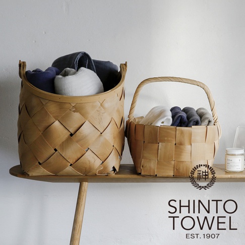 兩個編織木籃裡裝有捲起來的毛巾，顏色包含藍色、白色、灰色和深灰色。